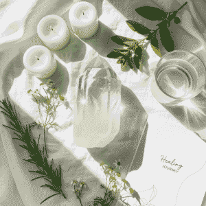 Flat lay of a clear quartz crystal surrounded by white linens, healing herbs, candles, and a journal titled 'Healing Journey,' styled in a clean, natural wellness setting to represent crystal healing for sickness and recovery.