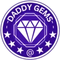 Circular logo for the online gemstone store 'Daddy Gems.' The design is white on deep purple, featuring the company name across the top, a large, stylized, white faceted diamond icon in the center, and a border of white stars. An "@" symbol is visible at the bottom.
